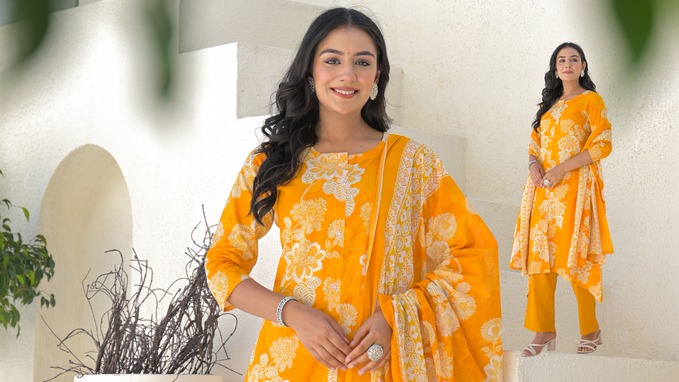 Woman wearing a yellow traditional outfit with floral patterns indoors.