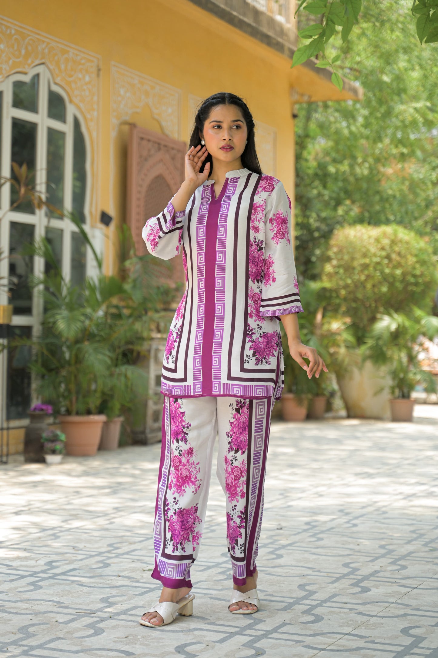 Woman wearing a coord set printed kurta set with geometric and floral patterns in pink and white.